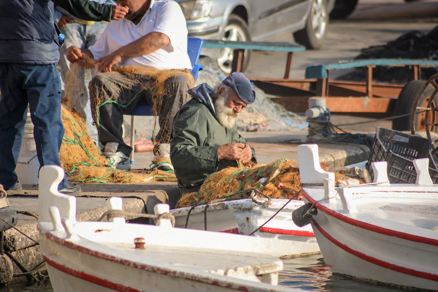 Des pêcheurs qui réparent leurs filets entre les barques amarrées