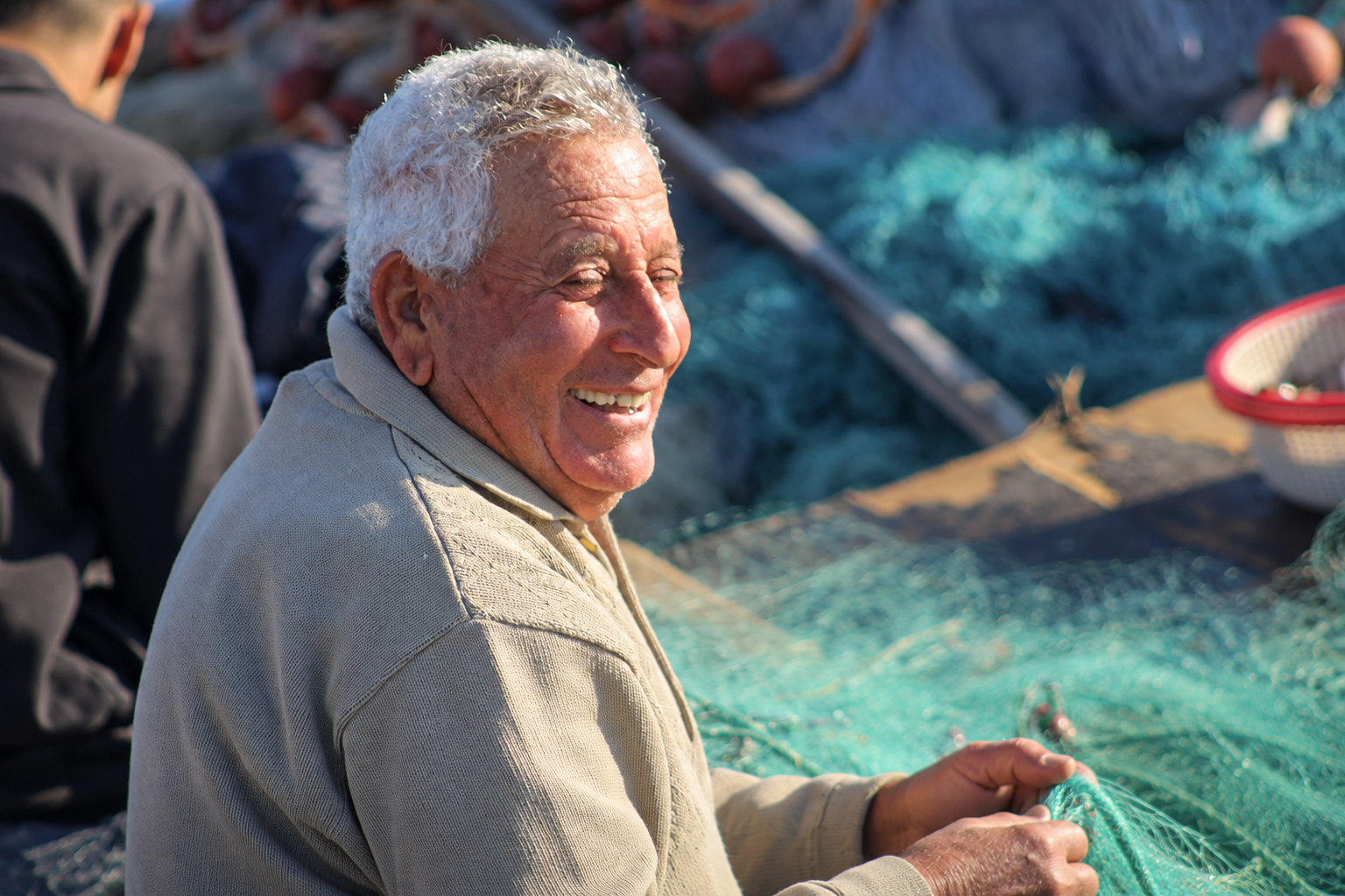Un pêcheur souriant qui répare un filet vert