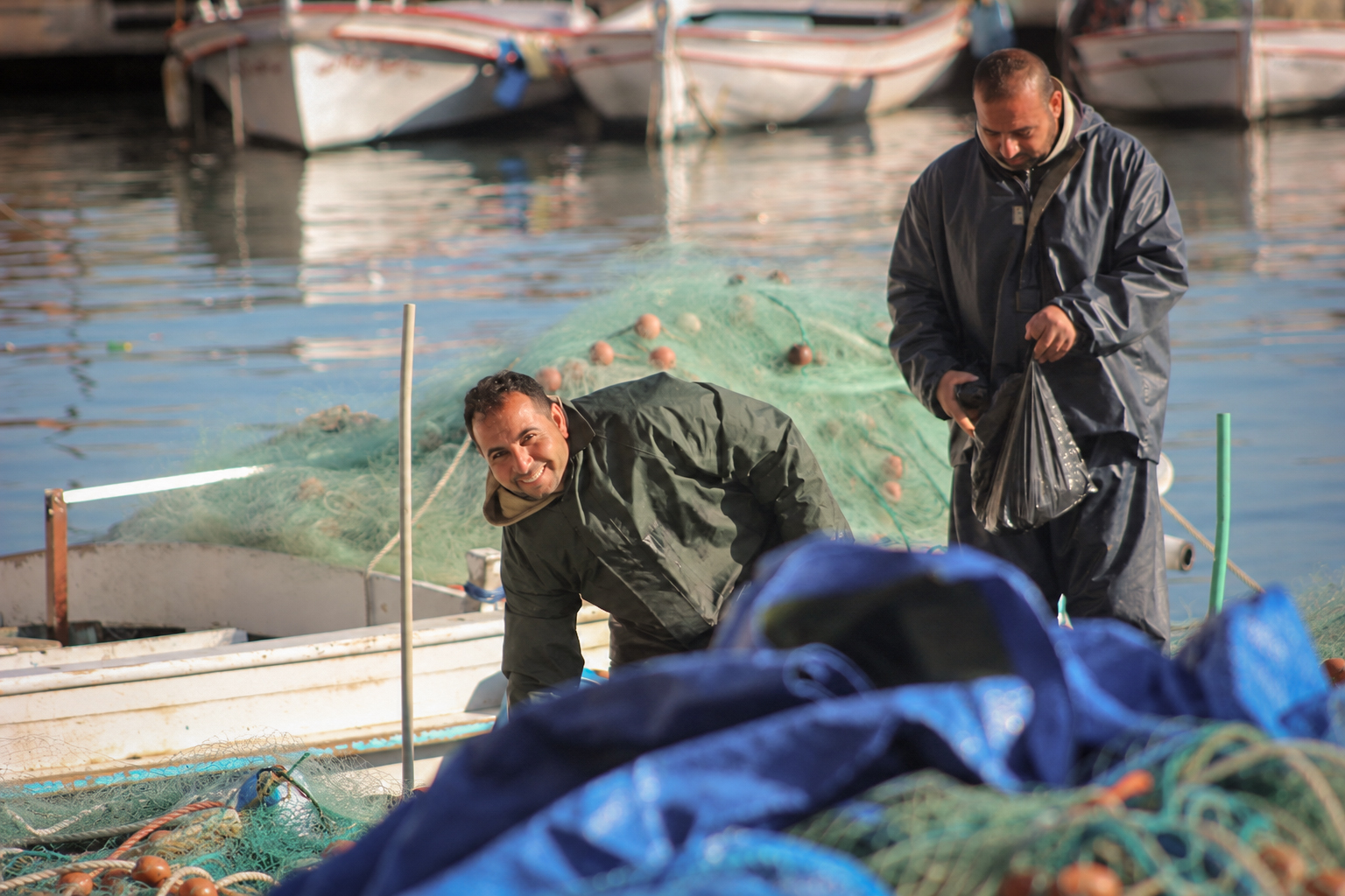 Deux pêcheurs qui trient filets et matériel sur une barque