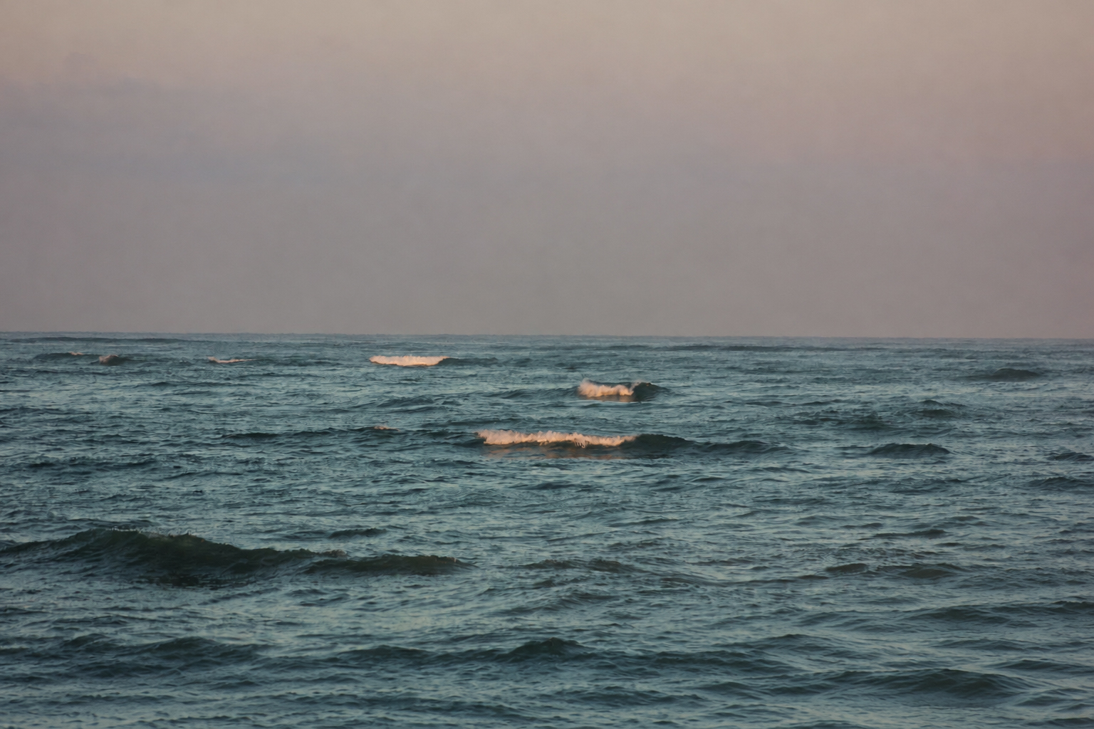 De petites barques au large, à l'aube