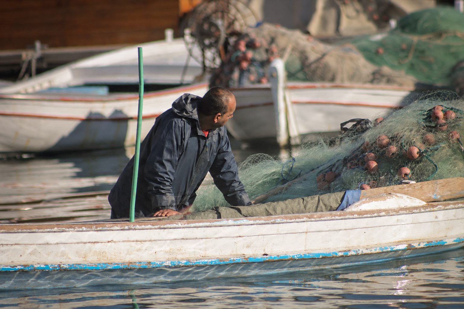 Un pêcheur debout dans sa barque, les filets empilés derrière lui