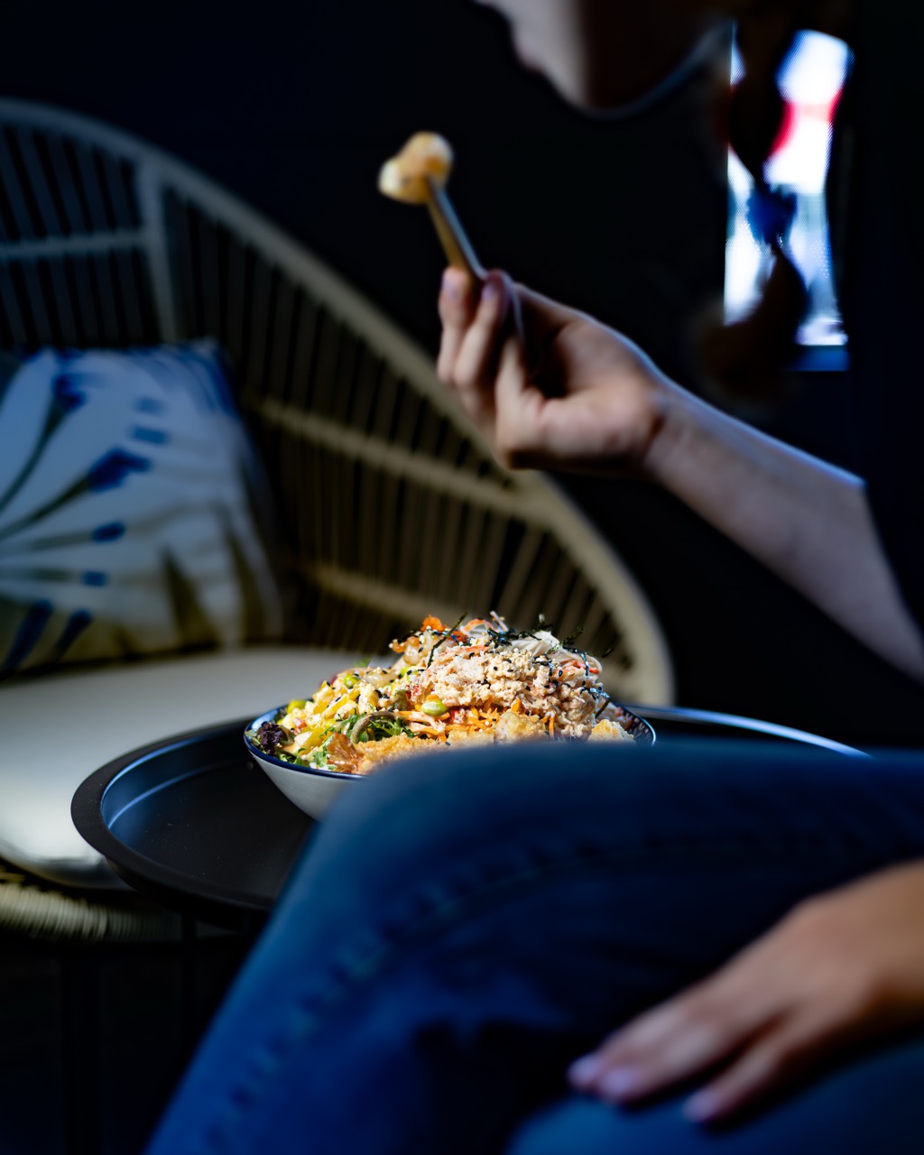 A person holding a bowl of fusion food, showcasing the fresh ingredients.